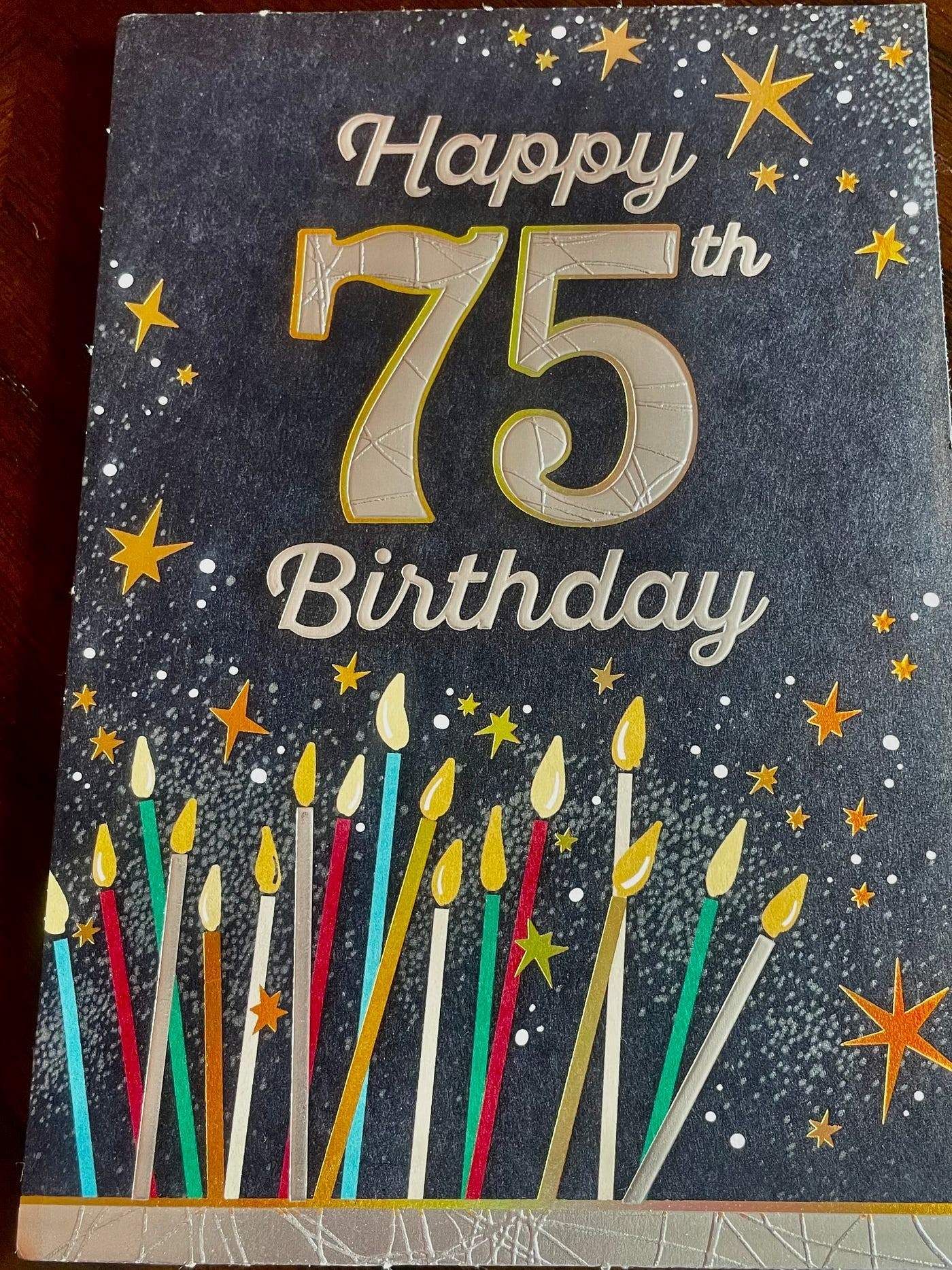 75th birthday card with a dark starry background, decorated with gold and silver stars and colorful candles