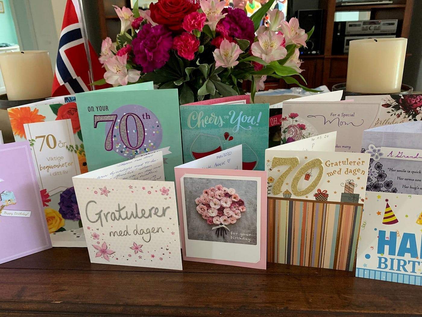 A collection of birthday cards displayed on a wooden table, many celebrating a 70th birthday